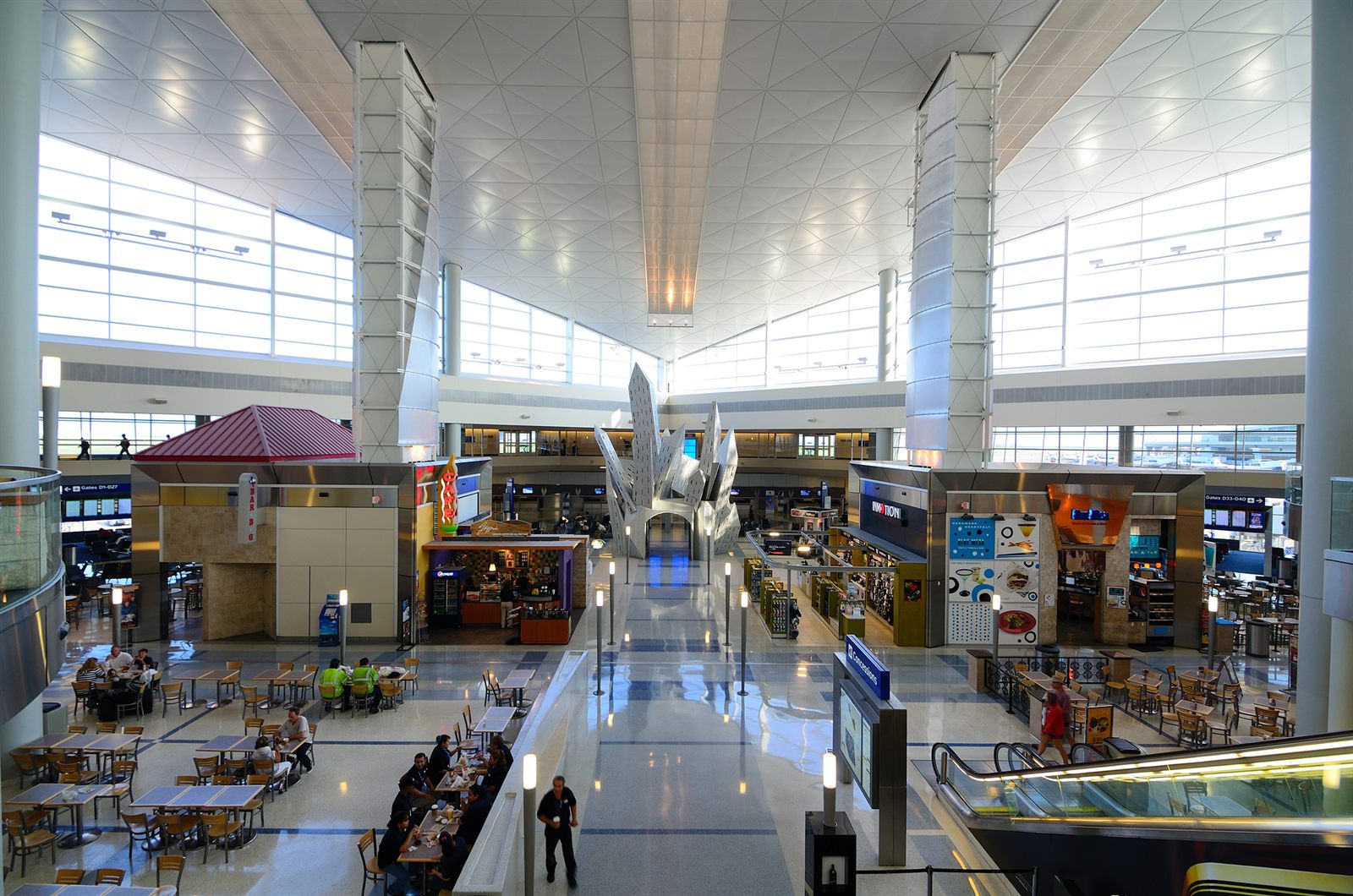 Shops and seating in a bright, high-ceilinged travel terminal hall